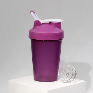 Close-up of purple protein shaker bottle with white lid and metal whisk ball on a stand