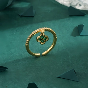 Exquisite gold four-leaf clover ring with green emerald zircon pendant on dark background