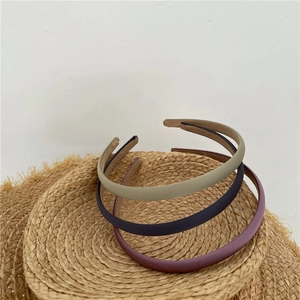 Detail view of solid color matte fabric headbands in green, navy blue, and burgundy