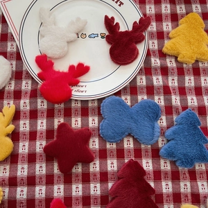 Flat lay of colorful Christmas plush patches in tree, star, and elk shapes for DIY