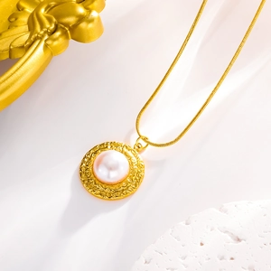 Macro detail of the vintage gold snake chain and the white shell pearl pendant design