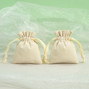 Beige cotton drawstring jewelry bags set against elegant green gauze backdrops