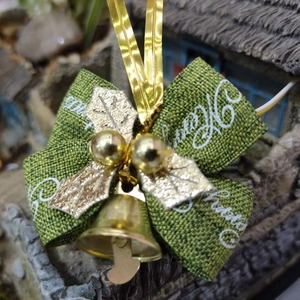 Close-up of green bow with golden bell and holly leaves for Christmas gift decoration