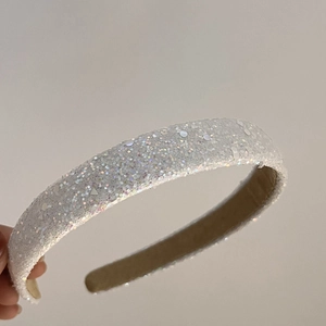Detailed view of a white shimmering headband with sparkling sequins and beige lining