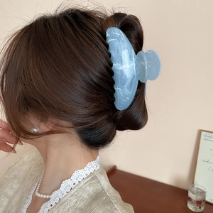 Détail d'une pince à cheveux en acrylique bleu clair marbré sur un chignon élégant
