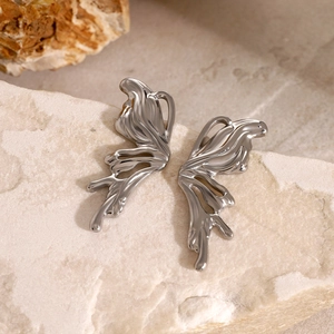 Macro shot of silver fluid metal butterfly earrings on a natural textured stone base