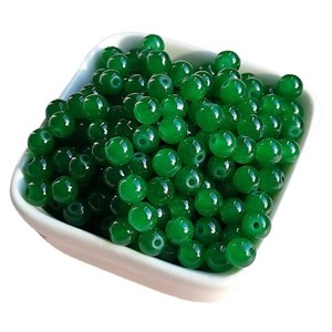 Translucent emerald green glass round beads for jewelry making in white square dish