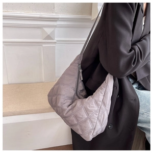 Close-up of grey quilted crossbody bag showing soft nylon fabric on a model