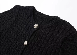 Detailed view of black knitted cardigan featuring two embossed silver metal buttons