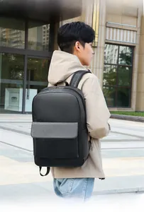 Side view of a minimalist black leather travel backpack worn by a model in the city