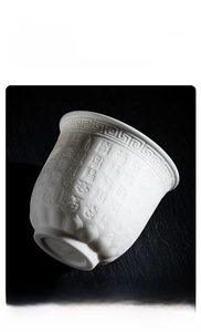 Macro detail of embossed Fu characters on premium sheep fat white jade porcelain teacup