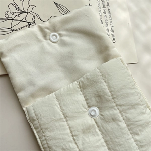 Detailed macro view of cream quilted fabric storage bag with secure white snap buttons
