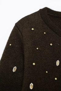 Detail of dark brown knit cardigan featuring luxury golden beads and crystal embellishments