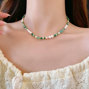 Detail of malachite and pearl beaded necklace on model neck with lace shirt