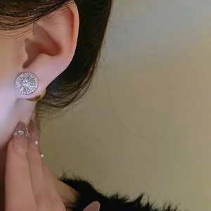 Gros plan de boucles d'oreilles dorées en forme de soleil avec zircons sur un mannequin