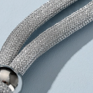 Macro detail of silver woven chain mesh with polished sphere connector for necklaces
