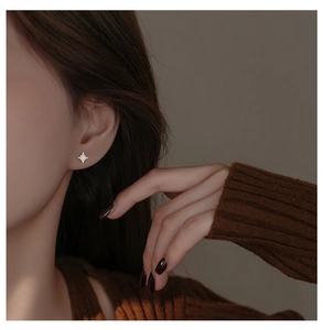 Close-up of elegant starburst silver stud earrings with zircon inlay worn by model