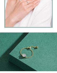 Macro detail of adjustable gold ring with clear gemstone and delicate bead chain