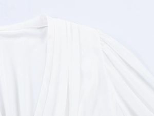 Détail de l'épaule d'un chemisier blanc montrant la texture du tissu et le design plissé