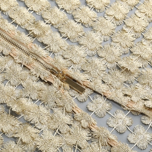 Detail of champagne gold floral embroidery with metallic zipper on a luxury dress