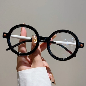 Détail des lunettes de soleil rondes noires avec branches blanches et rivets décoratifs