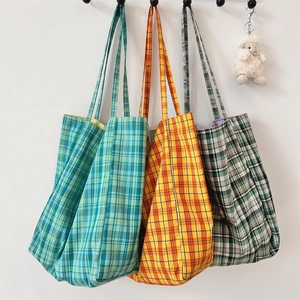 Three checkered canvas tote bags in green, orange, and gray hanging on hooks