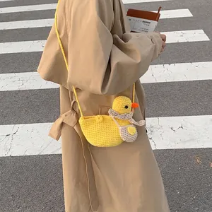 Handmade yellow knitted duck crossbody bag styled with a beige trench coat on street
