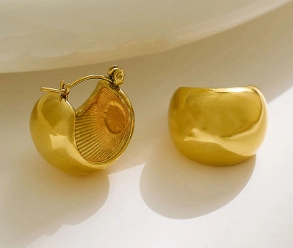 Detail of chunky gold hoop earrings with polished finish and radial textured interior