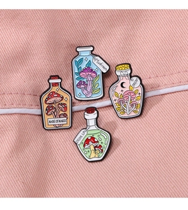 Detail of magical potion bottle enamel pins with mushrooms on pink denim background