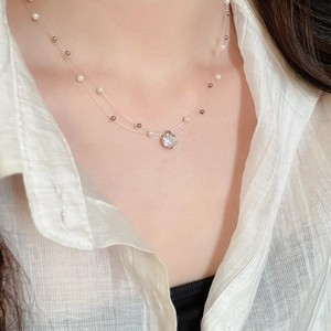 Macro view of double-layered invisible necklace with pearls and round zircon pendant