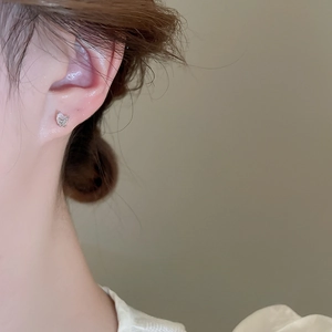Close-up of minimalist silver butterfly stud earring with textured wing details on ear
