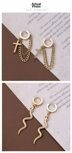 Detail of gold snake earrings with scale textures and cross chain fringe earrings