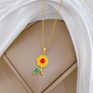 Gros plan d'un pendentif tournesol doré aux pétales colorés sur une fine chaîne en titane