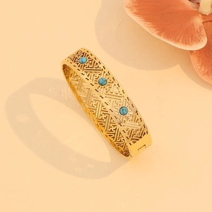 Detail of vintage gold hollowed bracelet featuring geometric patterns and turquoise gems