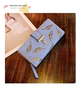 Detail of light blue faux leather wallet with hollow leaf patterns and golden pendant