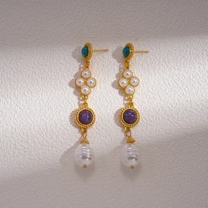 Detail of baroque pearl drop earrings with green and purple gemstones in gold vintage style