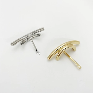 Close-up of minimalist U-shaped hair clips in polished silver and gold metal finish