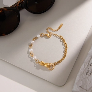 Détail d'un bracelet doré 18 carats avec des perles et un pendentif main unique