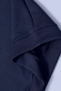 Detailed macro view of dark blue fabric with geometric 3D embossed texture on hoodie