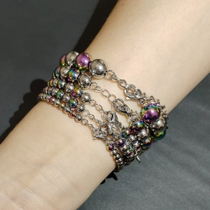 Détail d'un bracelet multicouche en acier inoxydable avec perles métalliques et irisées