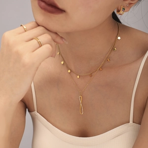 Double-layered gold necklace with flower charms and CZ-encrusted twisted bar pendant