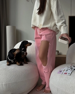 Gros plan sur un jean rose déchiré avec détails usés et un pull en maille blanc
