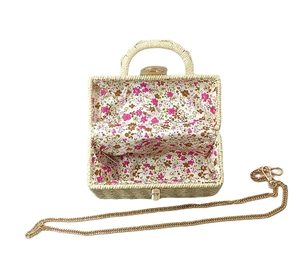 Chic woven top handle bag with gold chain strap and floral lining on a white background