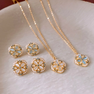 Detail of clover flower jewelry sets with blue and white stones in gold plating