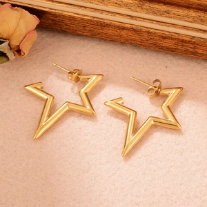 Gros plan de boucles d'oreilles dorées en forme d'étoile sur un décor en bois vintage