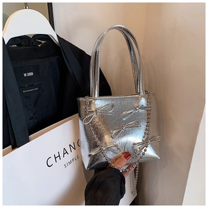 Detailed close-up of silver pleated handbag with bow accents and stylish chain decoration