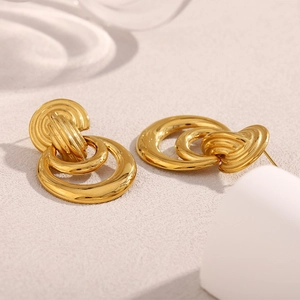 Boucles d'oreilles doubles anneaux en acier plaqué or 18K sur fond beige texturé