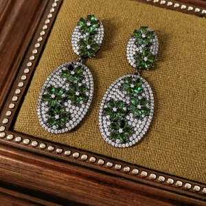 Detailed close-up of vintage flower earrings with green stones and zircon on velvet