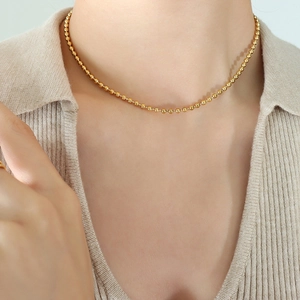 Minimalist gold ball chain necklace for women styled on a model with a beige knit shirt