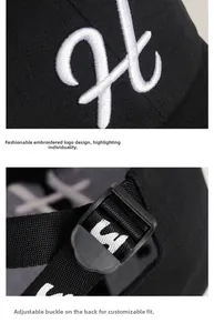 Detail of white embroidered logo and adjustable back buckle on black cotton baseball cap